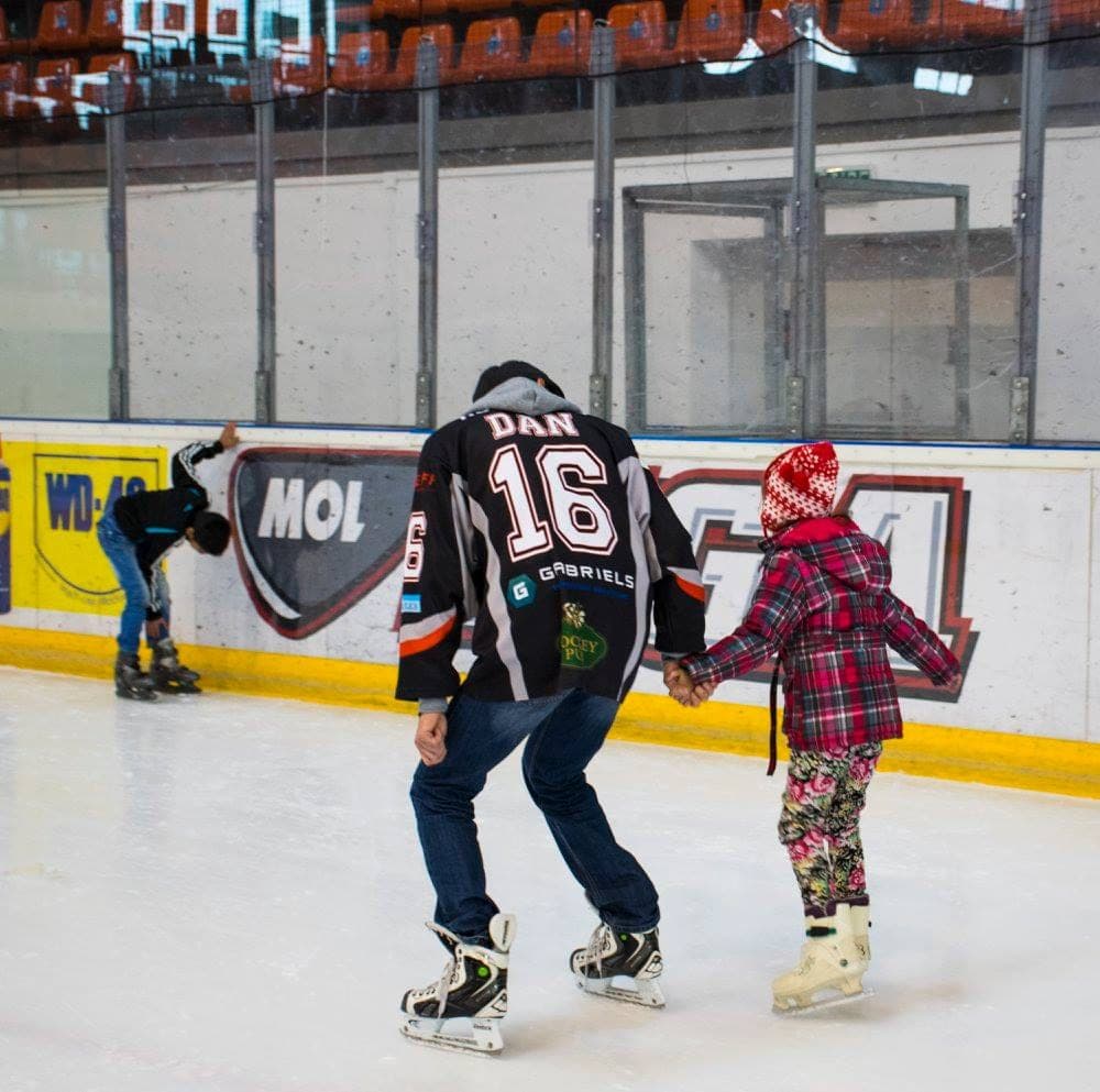 Un jucător Kronstadt Pub Boys patinează de mână cu o fetiță