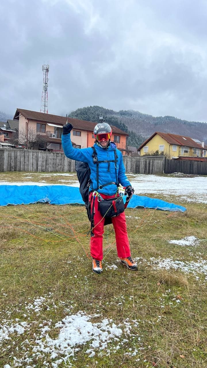 Pilot echipat cu harnașamentul face cu mâna, cu aripa întinsă în spate